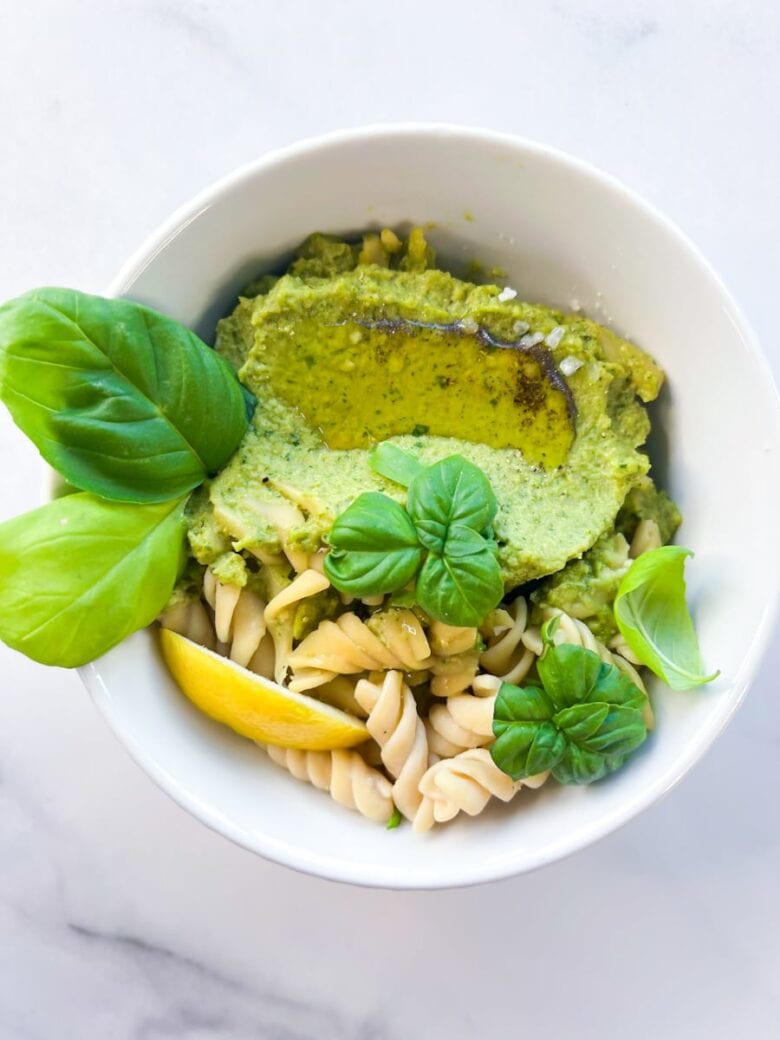 Cashew pesto pasta in a bowl with basil leaves.