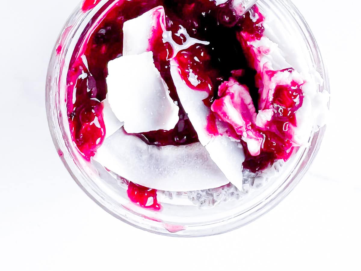 Chia pudding topped with berry compote and coconut flakes.