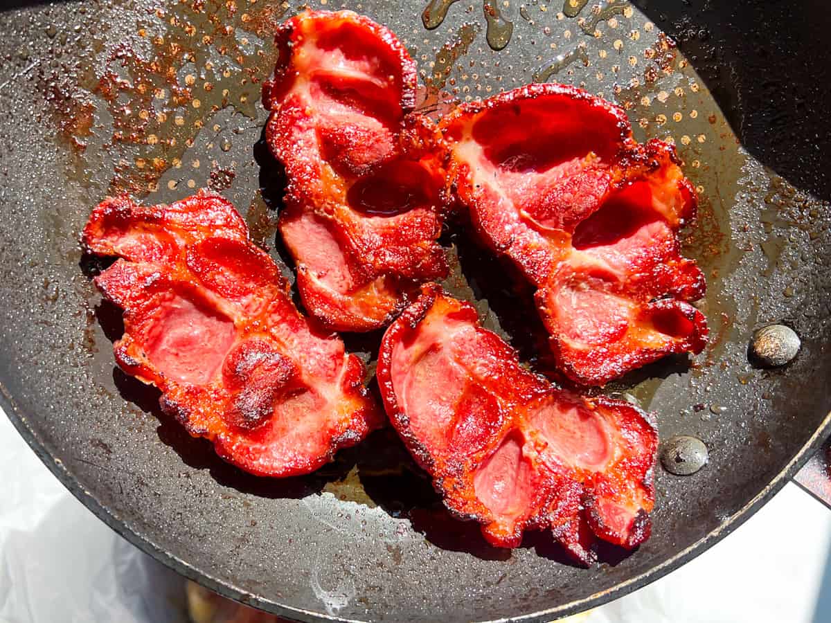 Bacon in a skillet being cooked.