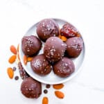 Chocolate covered date balls sitting on a small white plate.