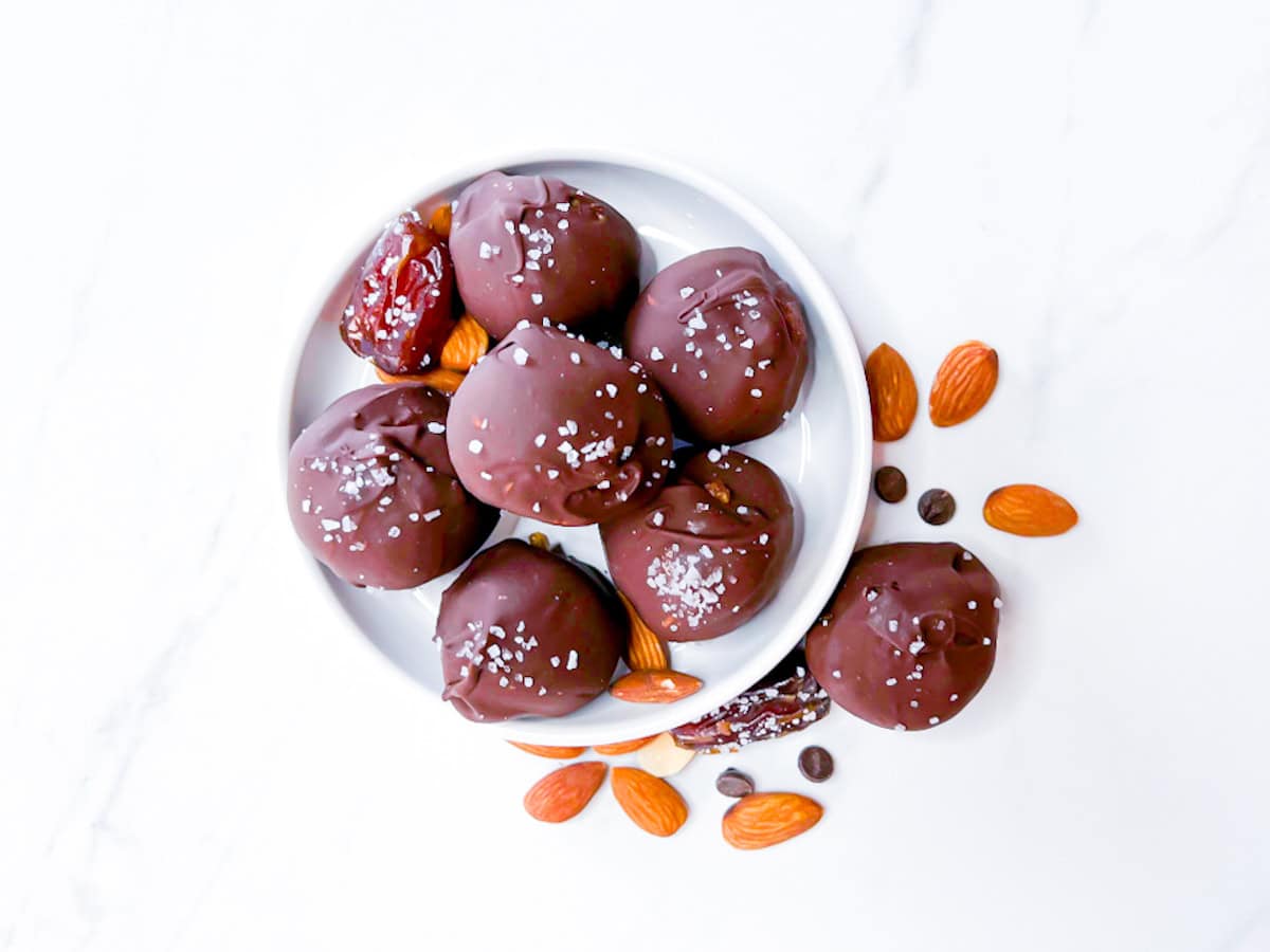 Finished chocolate date balls on a small white plate.