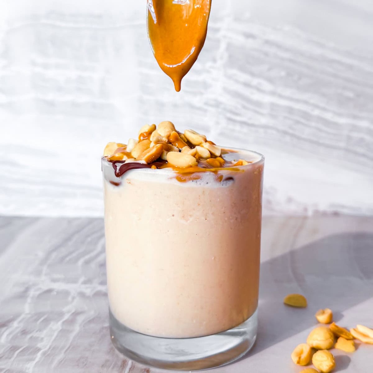 Peanut butter smoothie with chocolate, peanuts, and peanut butter drizzle.