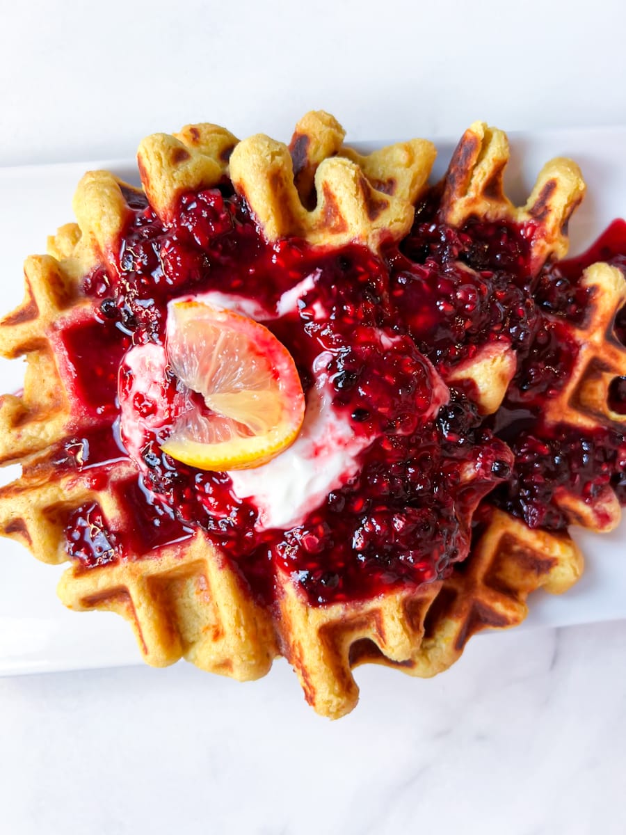 Oat flour waffles with berries on top.