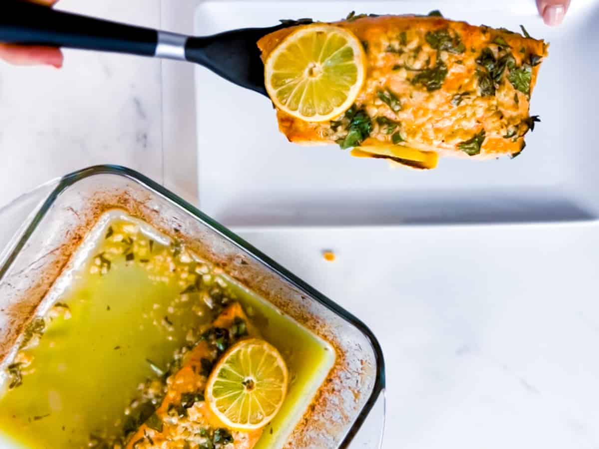 Mediterranean salmon being served on a white plate from a dish.