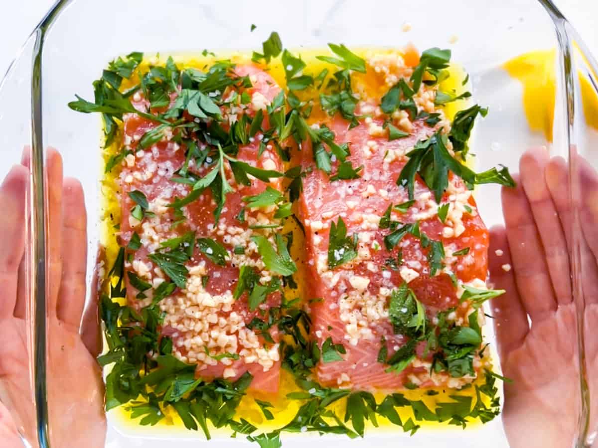 Herbs in dish over top salmon.