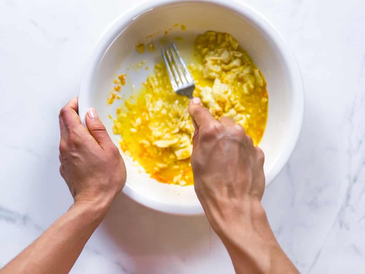 Mashing banana in a bowl for oat flour waffles.