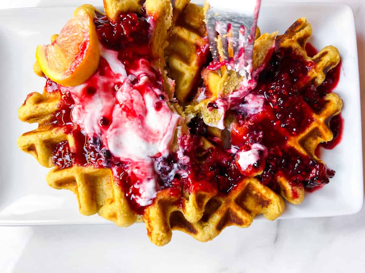 Healthy oat flour waffles being eaten with a fork.