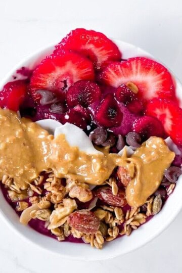Smoothie bowl with fruit, peanut butter, and granola on top.