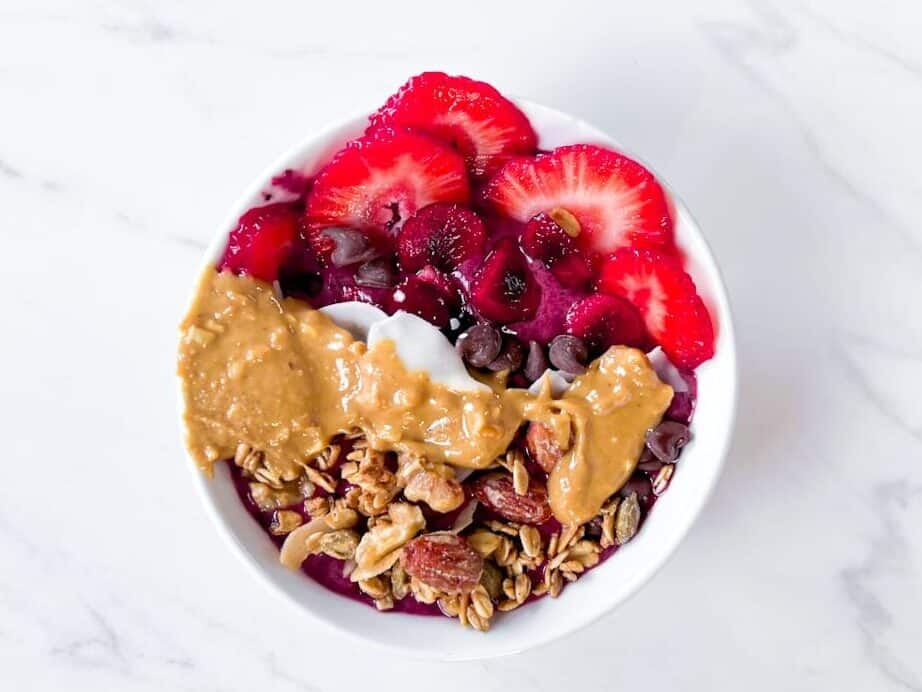 Smoothie bowl with fruit, peanut butter, and granola on top.