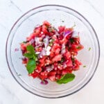 Finished watermelon salad with feta and fresh mint in a clear bowl.