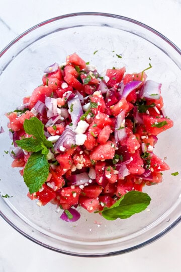 Finished watermelon salad with feta and fresh mint in a clear bowl.