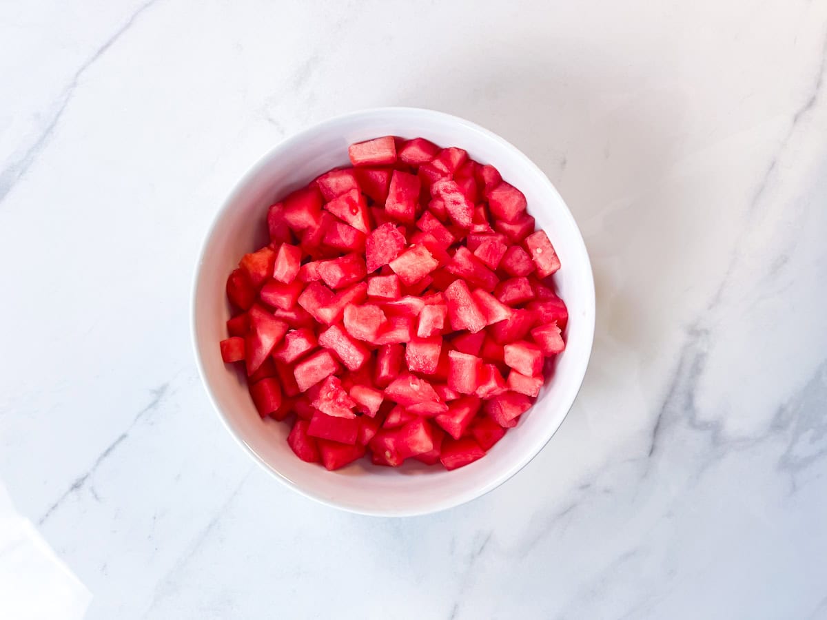 Watermelon cut up into small cubes in a bowl.