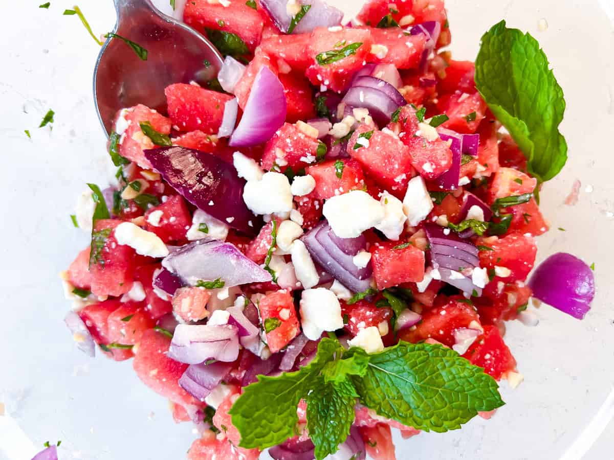 Finished watermelon feta and fresh mont salad in a clear bowl.