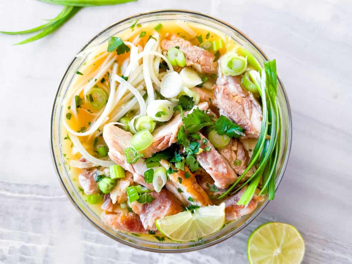 Asian chicken noodle soup in a clear bowl.
