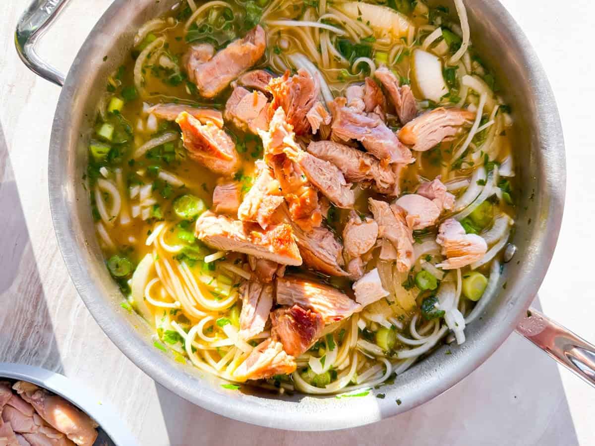 Chicken being added to the asian noodle soup broth.