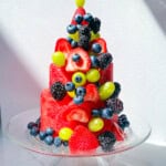 Finished layered watermelon cake topped with fresh berries and grapes.