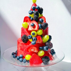 Finished layered watermelon cake topped with fresh berries and grapes.