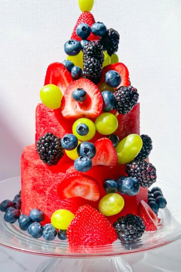 Finished layered watermelon cake topped with fresh berries and grapes.