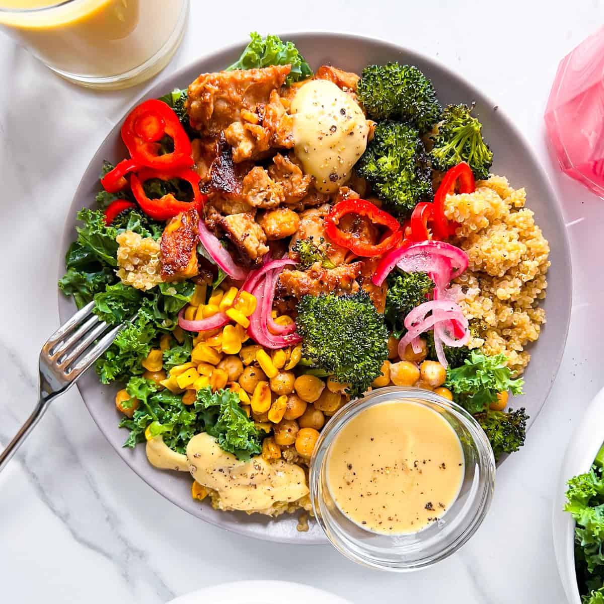 Roots style bowl with broccoli, quinoa, chicken, corn, and a creamy sauce.