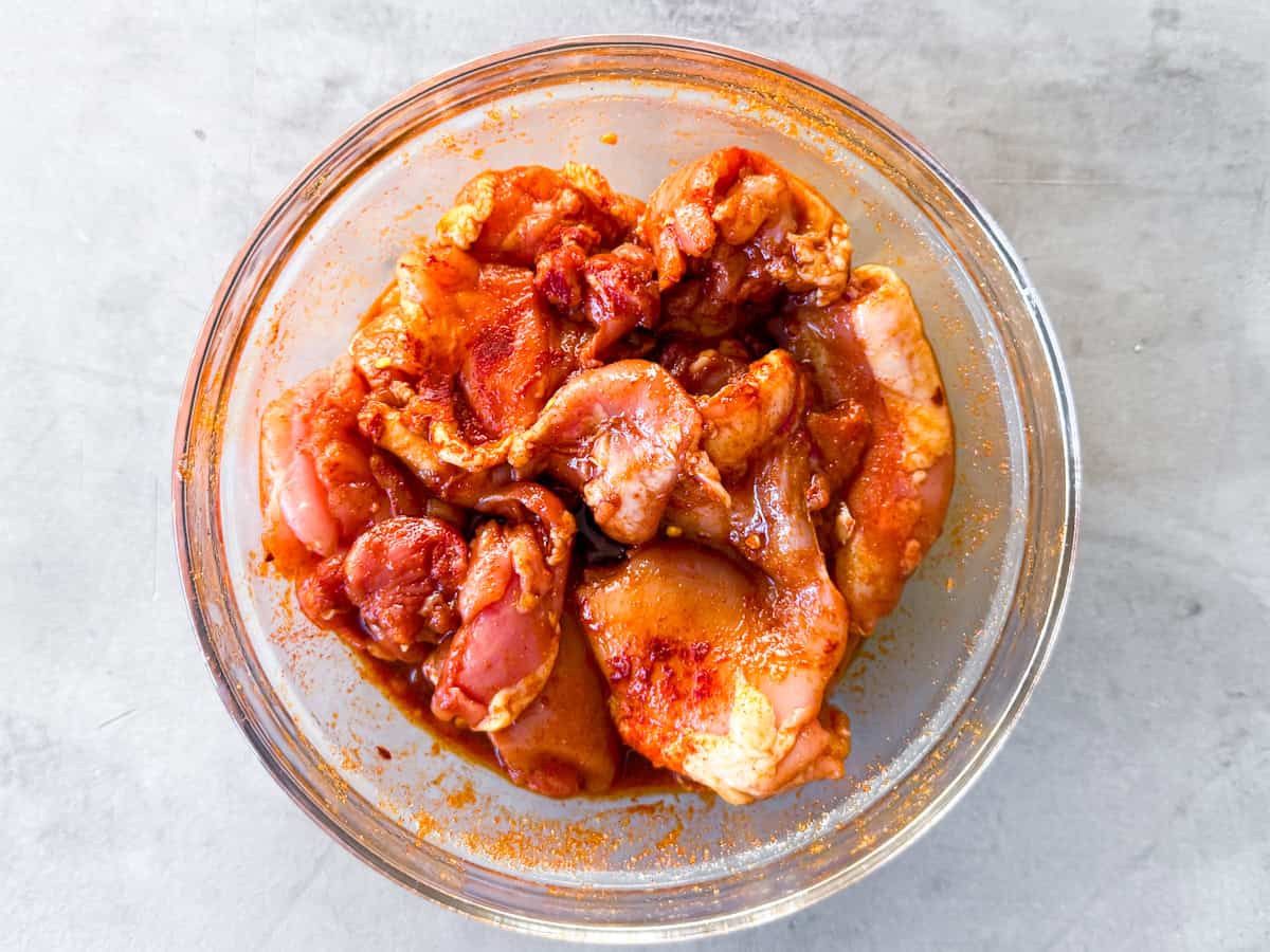 Raw chicken marinating in blackened chicken seasonings.
