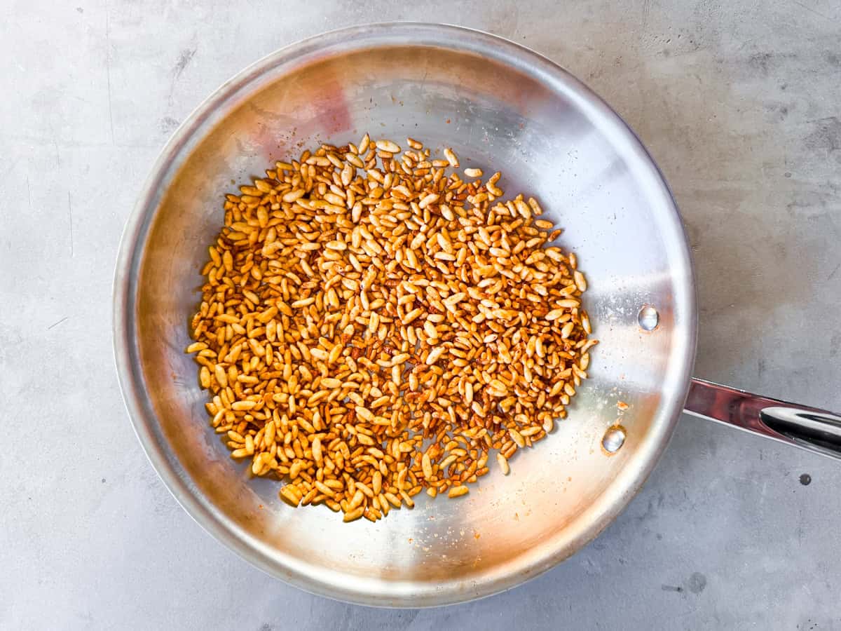 Puffed rice coated in tamari and spices browning in a pan.