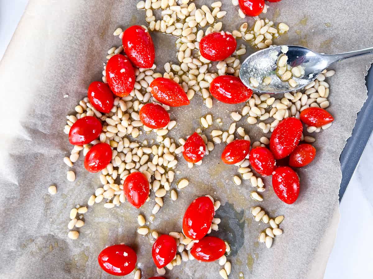Tomatoes and pine nuts on a baking sheet.