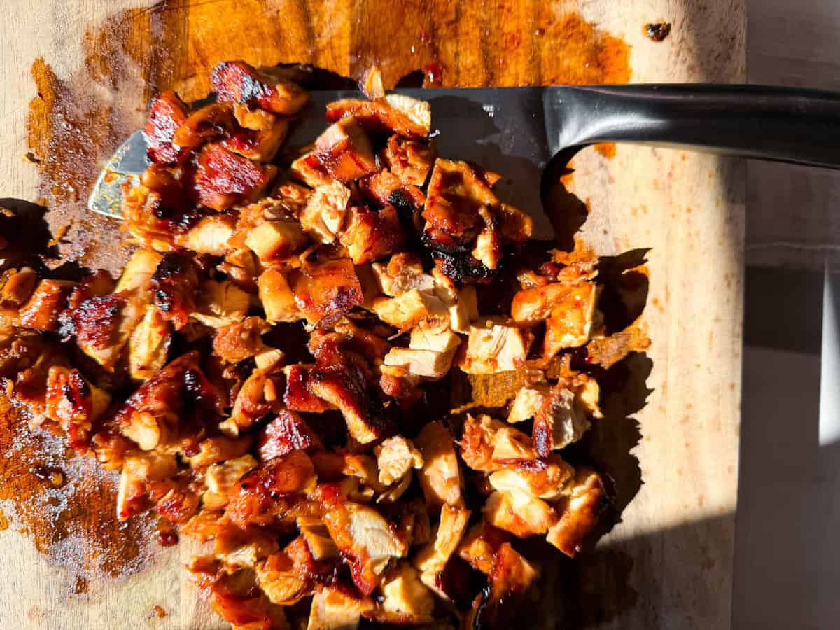 Grilled chicken thighs cut up on a cutting board.