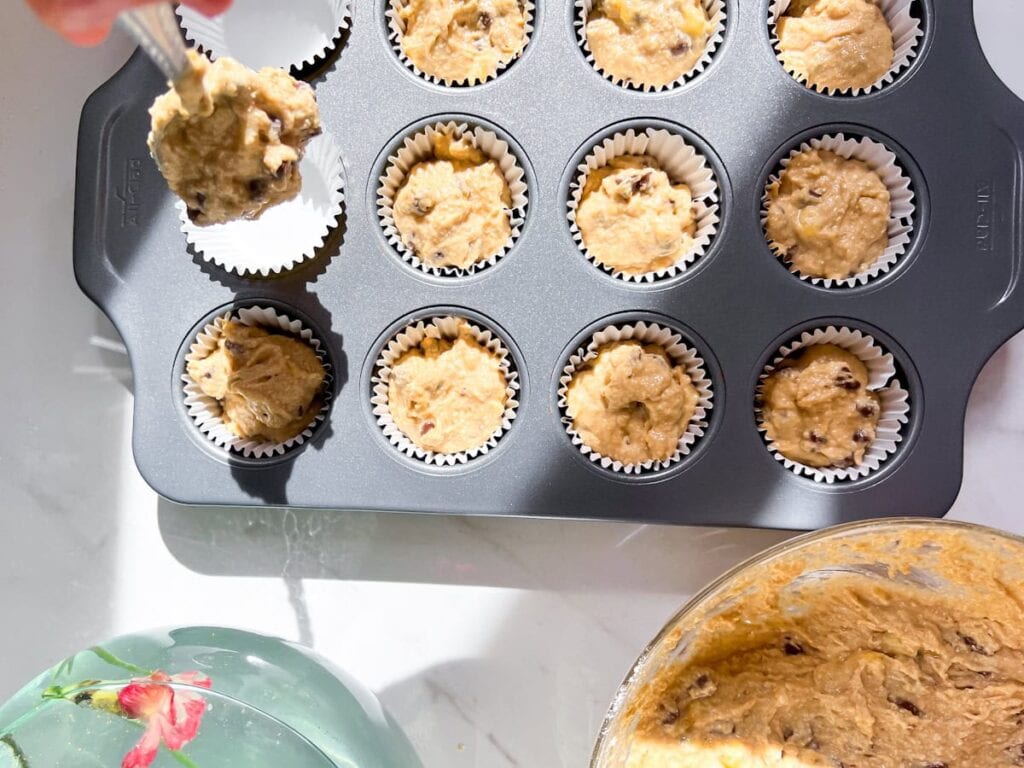 Adding the banana muffins to a pan.