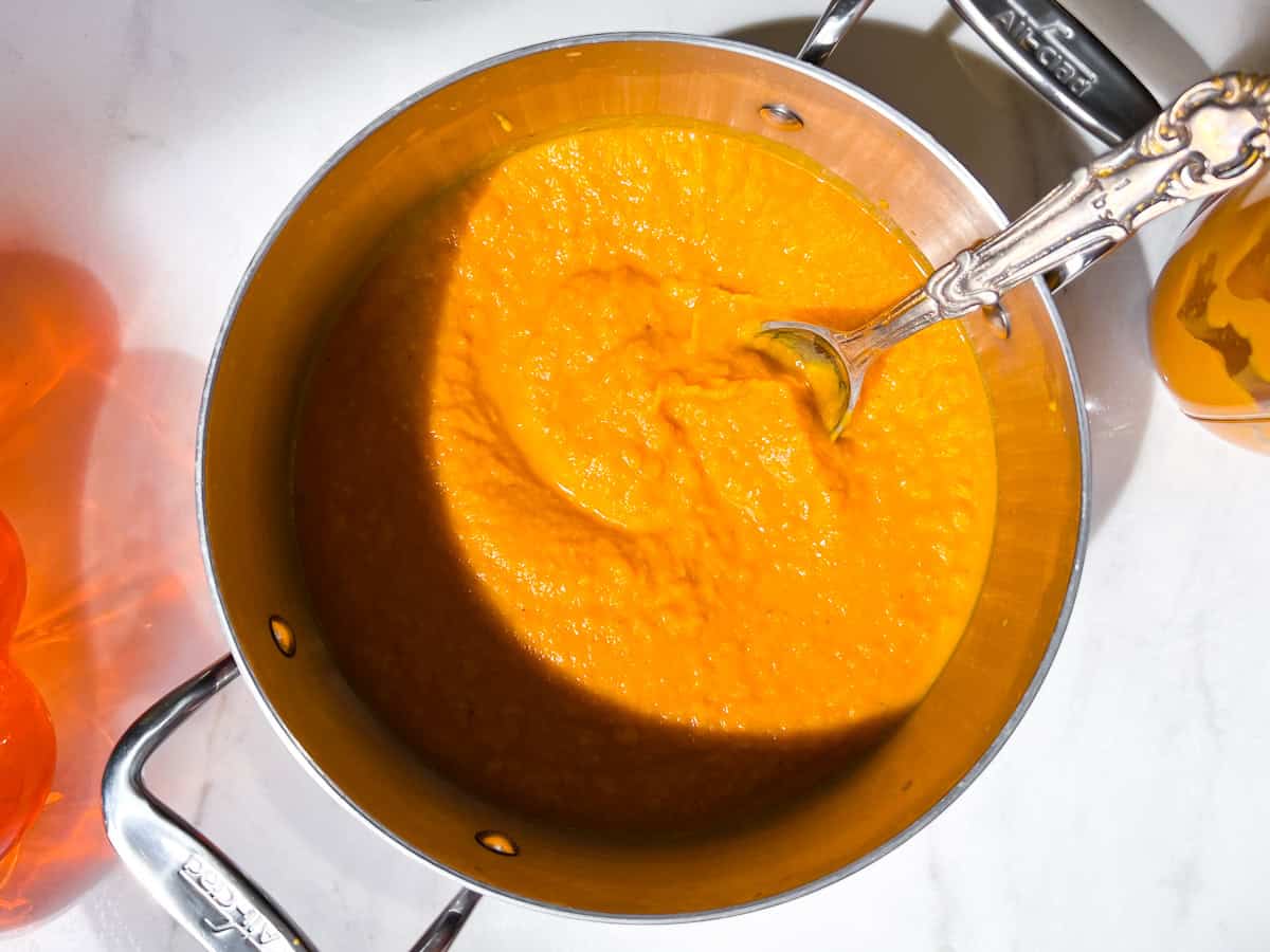 Blended butternut squash and carrot soup in a small pot,