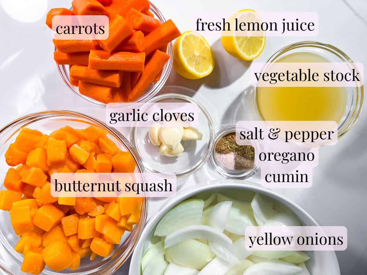 Butternut squash, carrots, onions, spices, garlic cloves, lemon, and spices in small bowls.