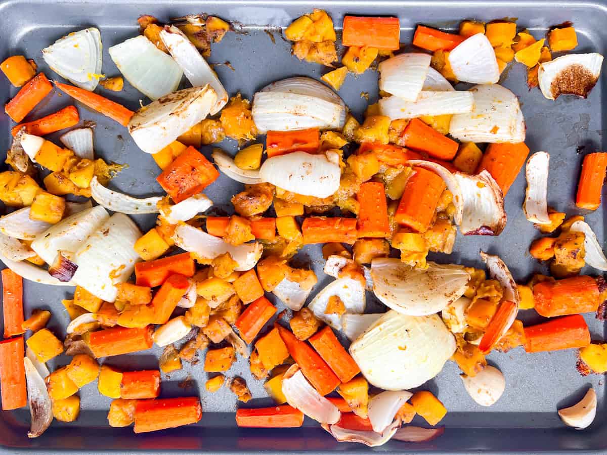 Roasted carrots, butternut squash, and onions on a sheet pan.