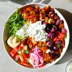 Cava style bowls with harissa chicken, hummus, arugula, and tzatziki.