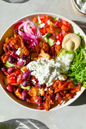 Cava style bowls with harissa chicken, hummus, arugula, and tzatziki.