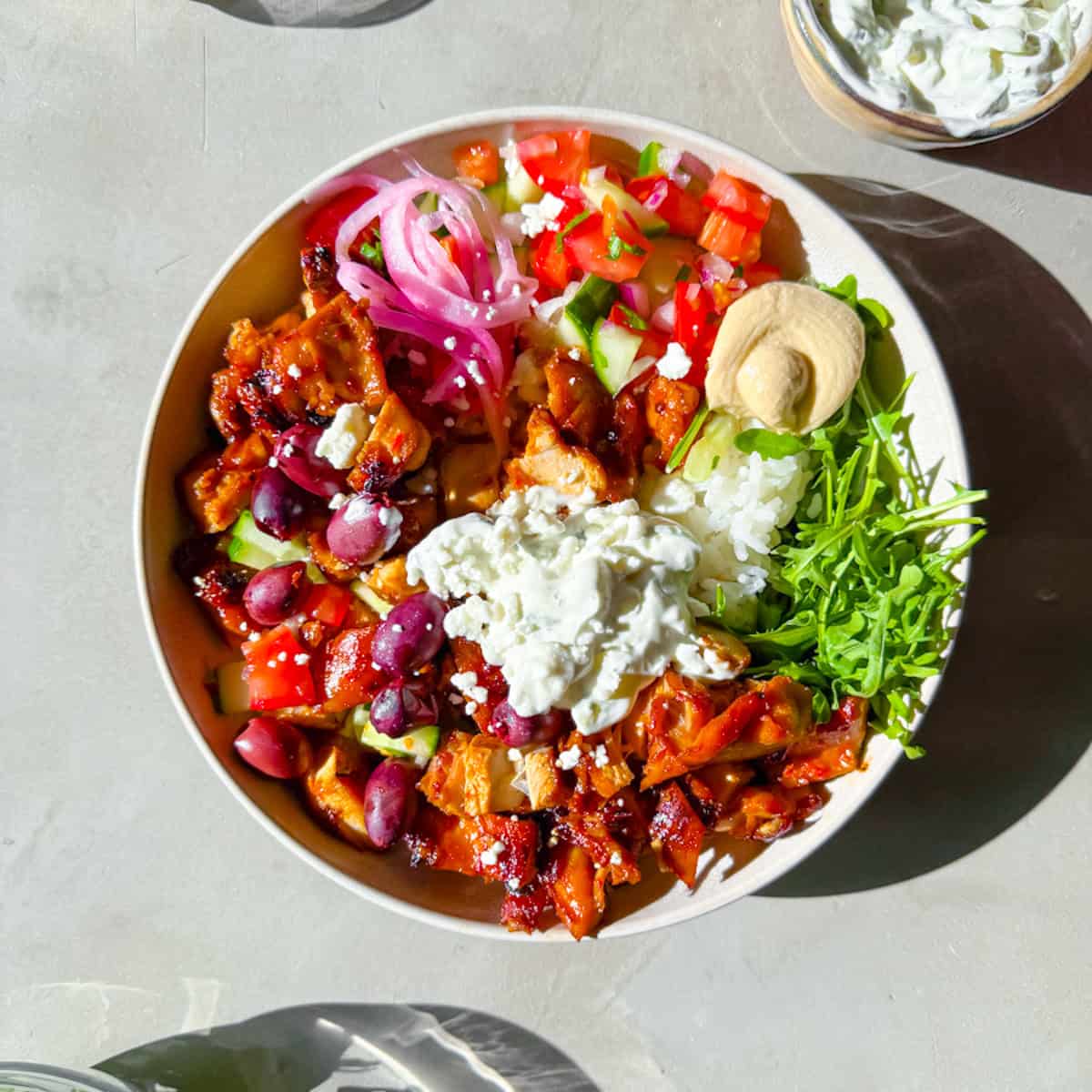 Cava style bowls with harissa chicken, hummus, arugula, and tzatziki.