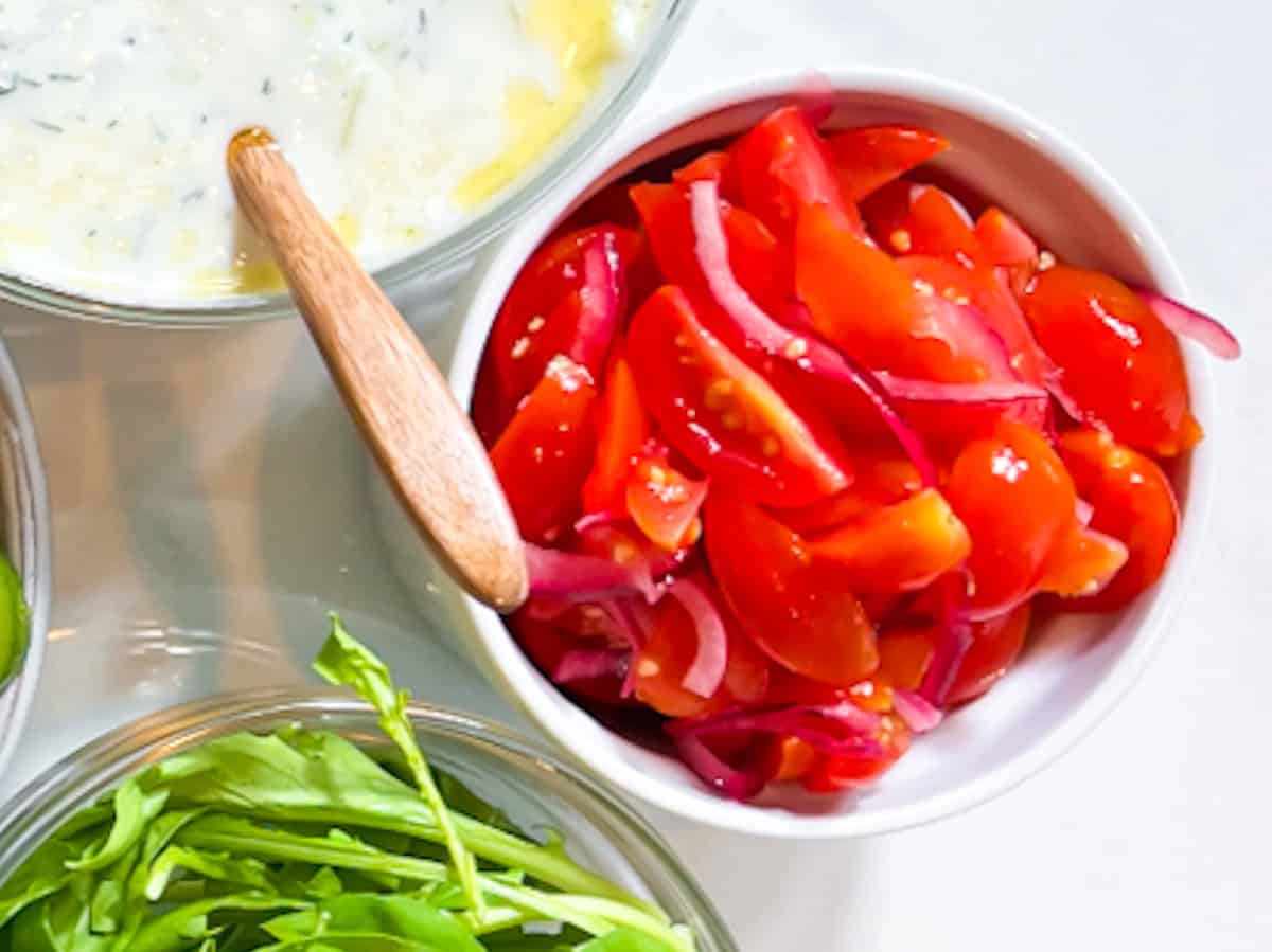 Tomato and onion salad in a white bowl.