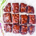 Gluten free brownies cut into pieces on white parchment paper.