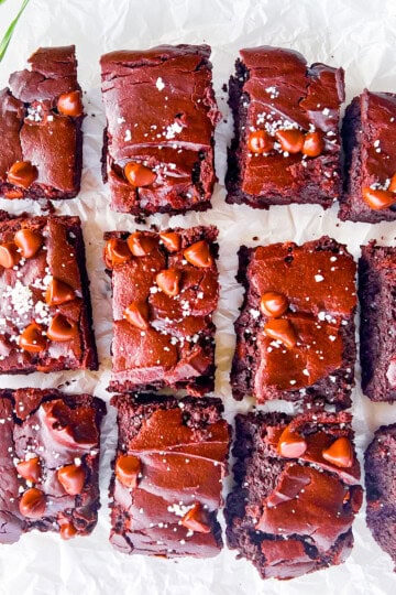 Gluten free brownies cut into pieces on white parchment paper.