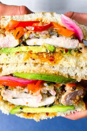 Chicken Katsu Sandwich with veggies and avocado being held.