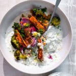 Tzatziki bowls with roasted potatoes in a white bowl.