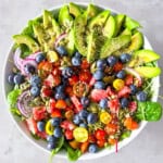 Arugula and spinach salad with avocado, vegetables, and fruit.