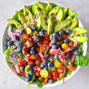 Arugula and spinach salad with avocado, vegetables, and fruit.
