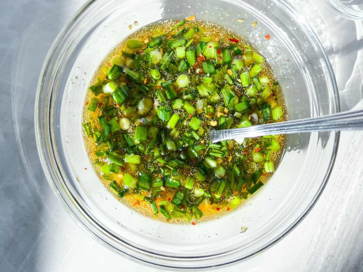 Honey, chili crunch, green onions, and sesame seeds combined in a bowl.