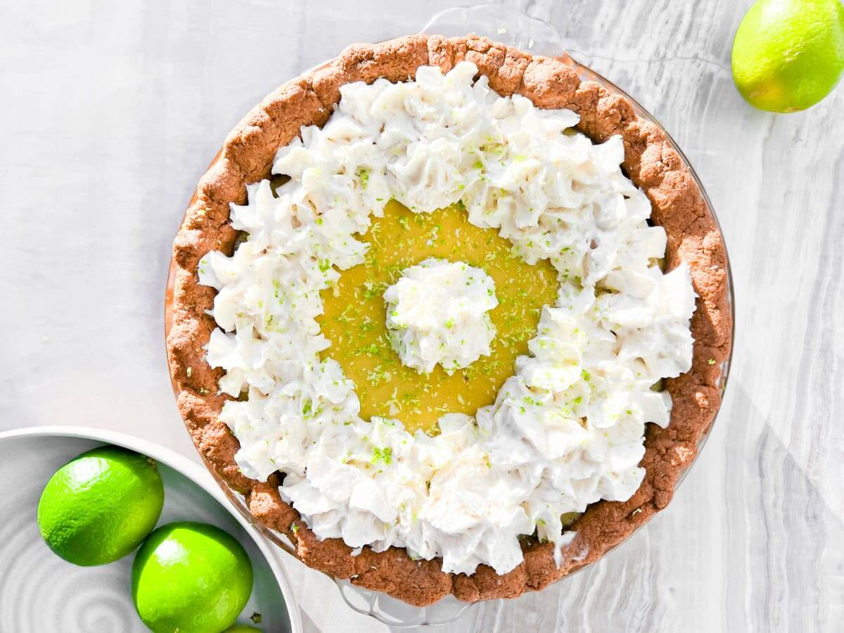 A key lime pie with limes around it.