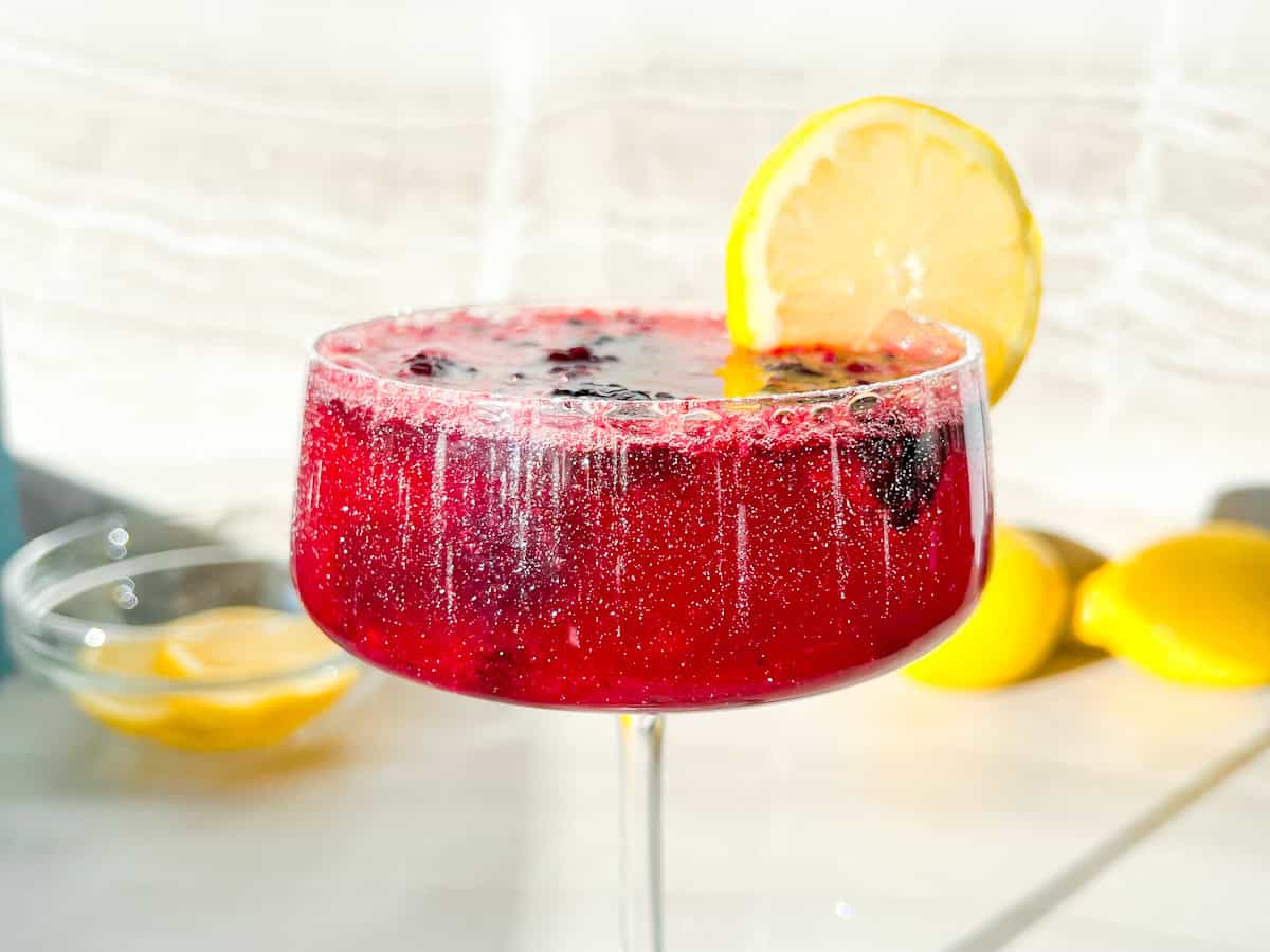 Finished blackberry mocktail garnished with a lemon.
