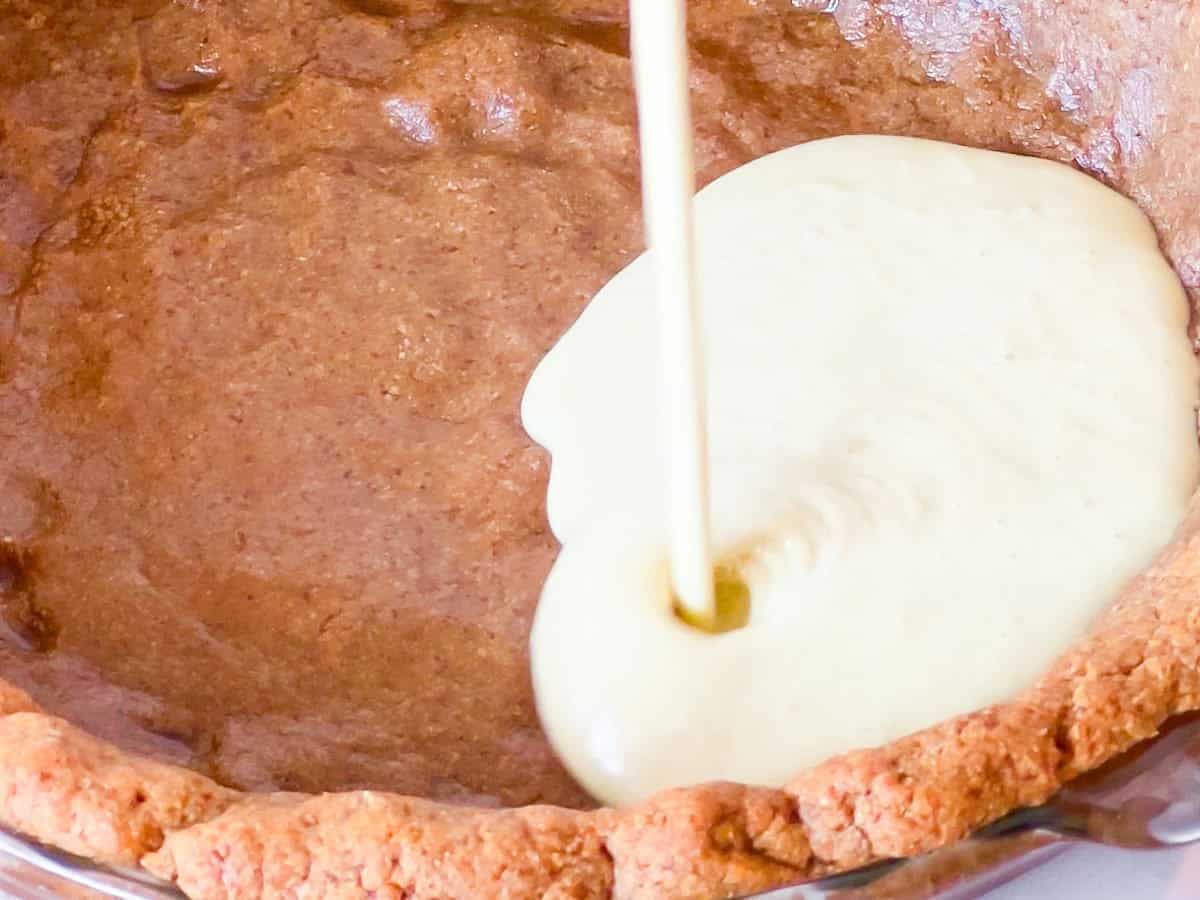 Key lime pie filling getting poured into the crust.