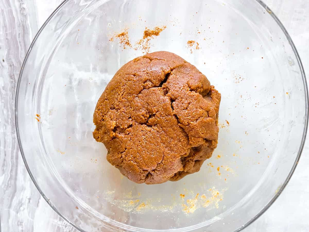 The key lime pie crust mixed and rolled into a ball sitting in the clear bowl.