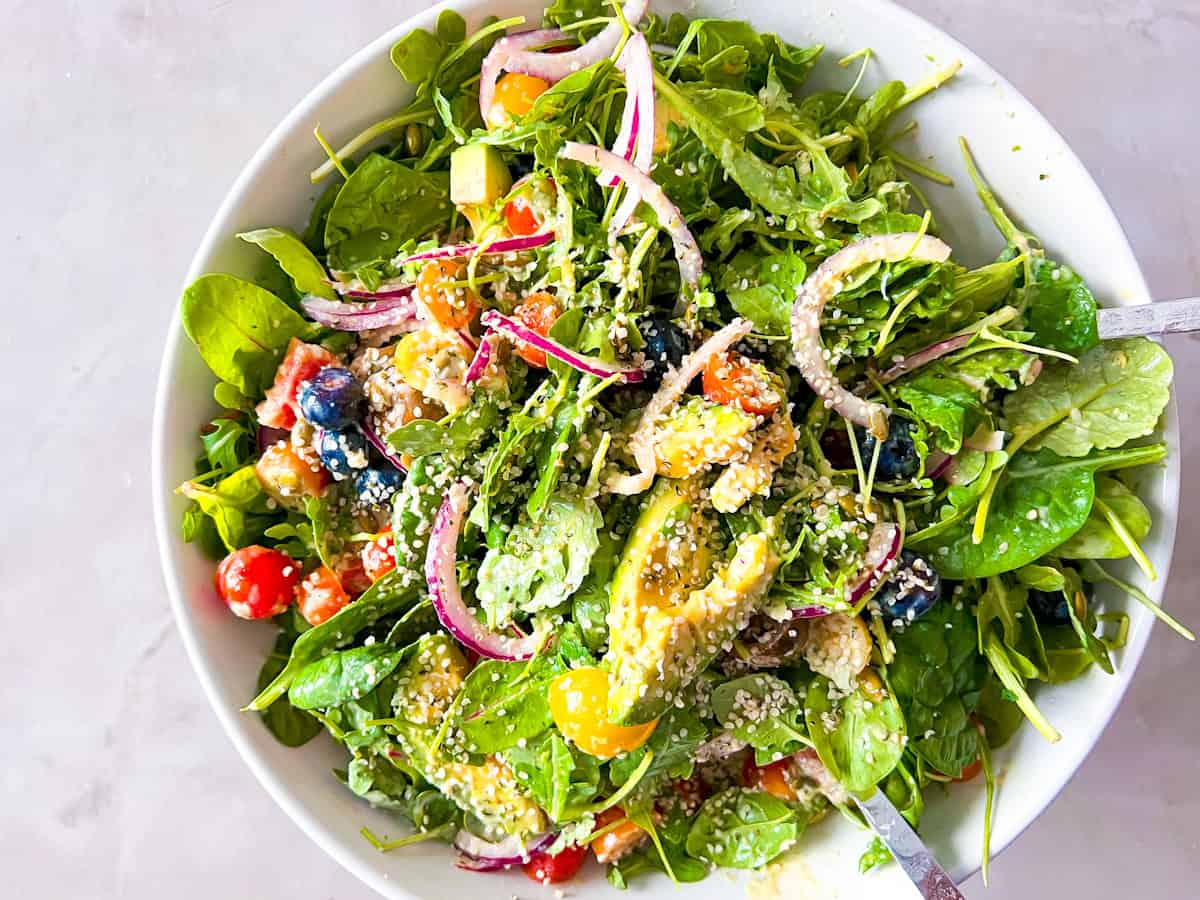 Tossed spinach and arugula salad in a large bowl.