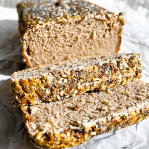 Loaf of buckwheat bread sitting on parchment paper and sliced.