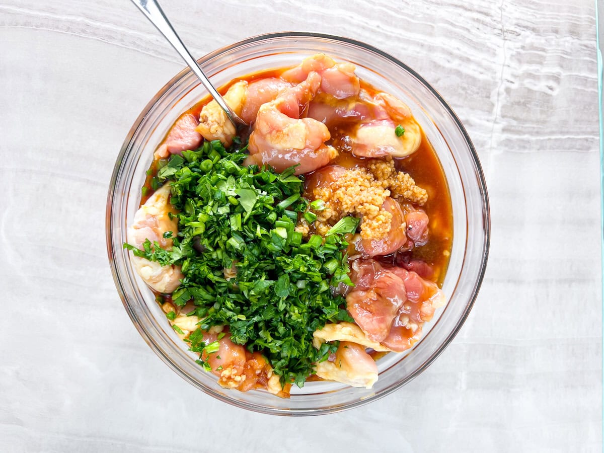 Chicken thighs marinating in tamari, cilantro, and sesame oil.