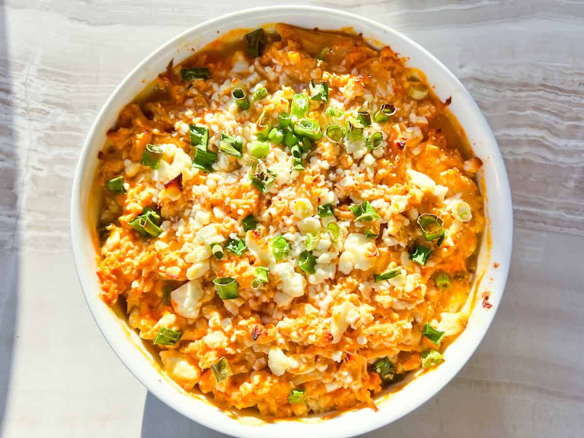 Fully baked high protein buffalo chicken dip in a white bowl.